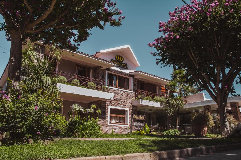 un edificio de apartamentos con flores delante en Hotel Gloria en Santa Rosa de Calamuchita