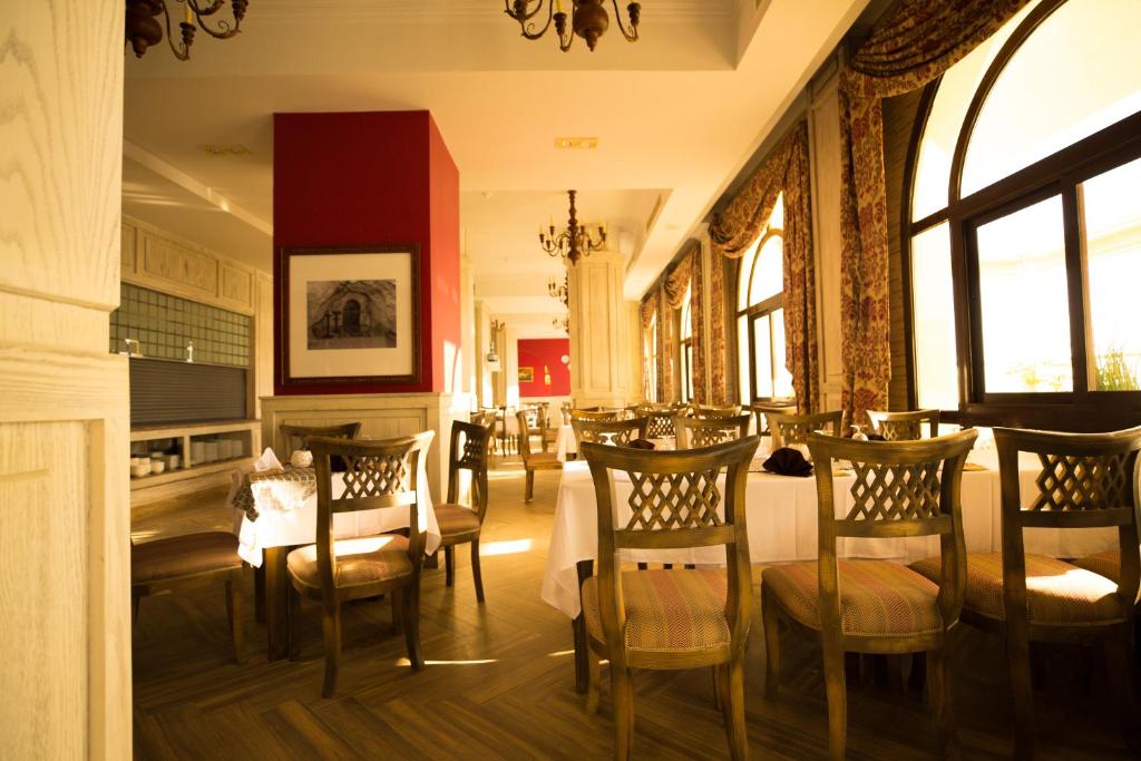 a dining room with tables and chairs and windows at Holy Family Hotel in Jabal aţ Ţayr