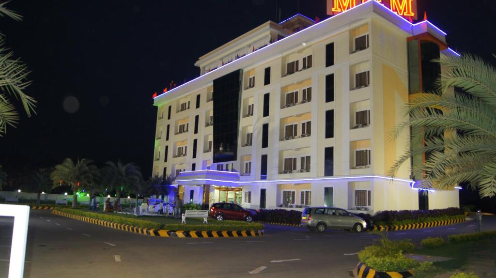un gran edificio blanco con coches estacionados frente a él en Hotel MGM Grand, en Srikalahasti
