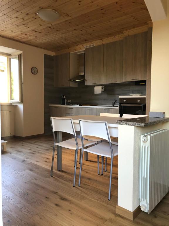 una cocina con sillas blancas y una isla de cocina en Appartamenti la muraca en Capizzone