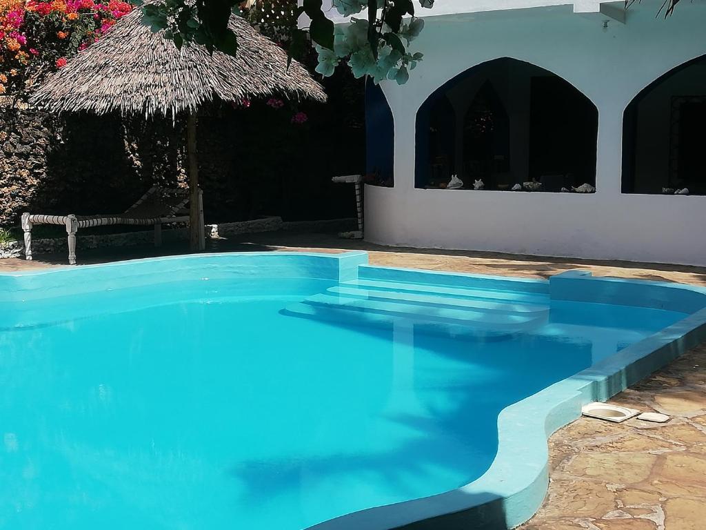 a blue swimming pool in front of a house at Chiky Villa in Watamu