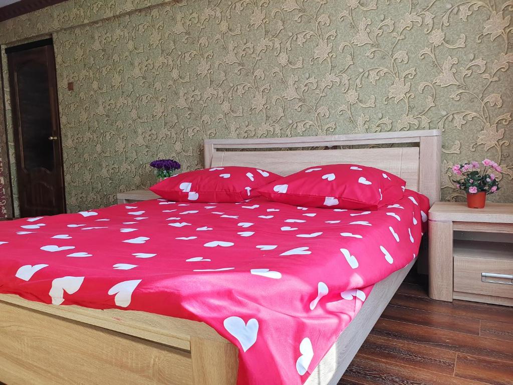 a bed with a pink comforter and pillows at Уютная Однушка in Atyraū