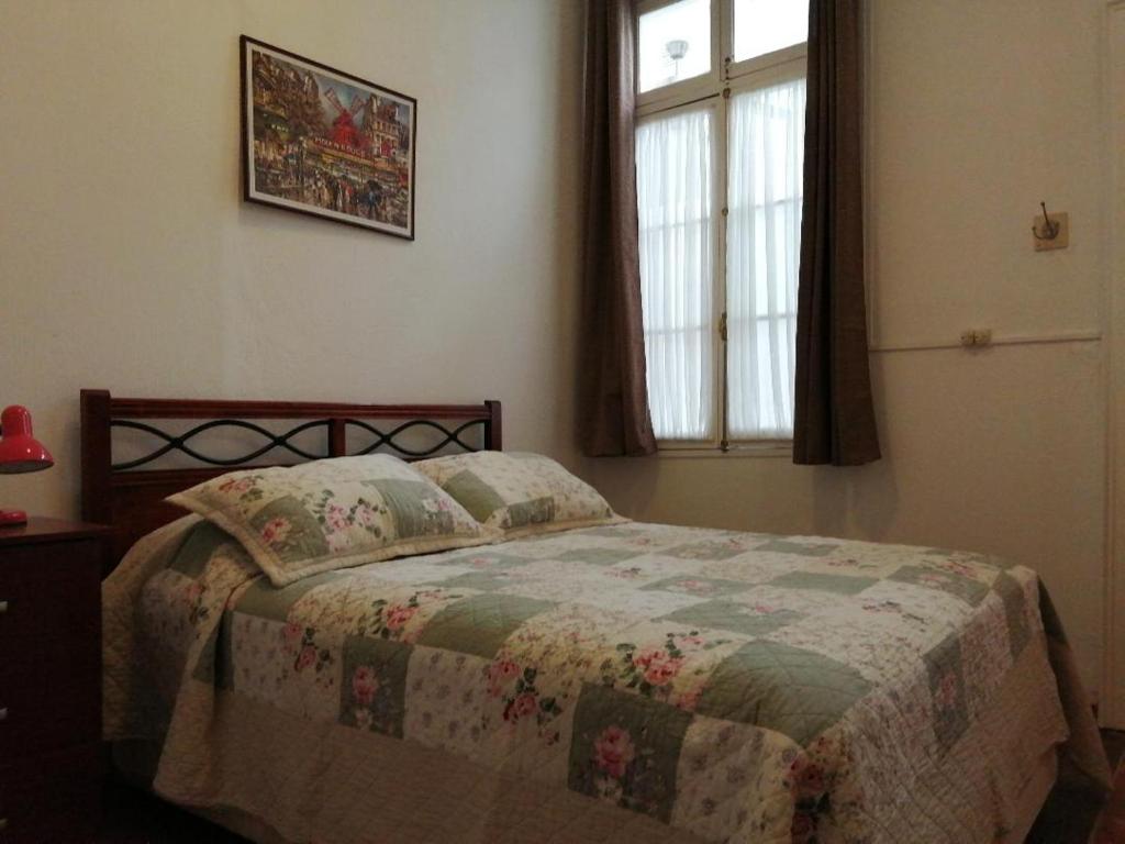 a bedroom with a bed with a quilt and a window at La Otra Vista in Valparaíso