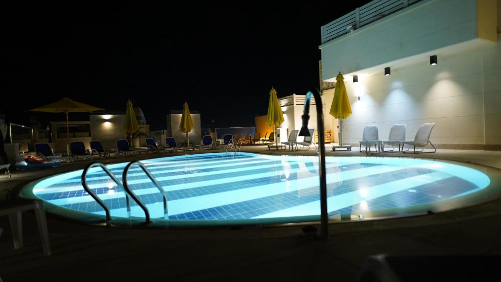 a swimming pool at night with chairs and umbrellas at Holy Family Hotel in Jabal aţ Ţayr