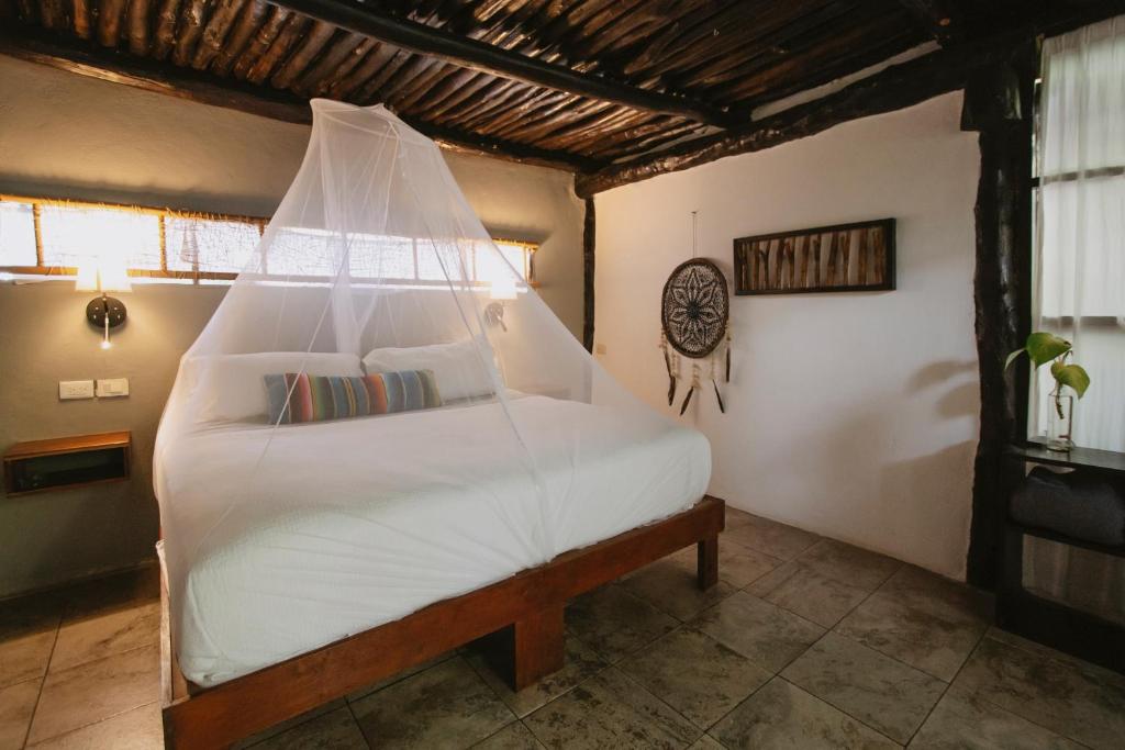 um quarto com uma grande cama branca e rede mosquiteira em Tunich Jungle Cabañas em Tulum