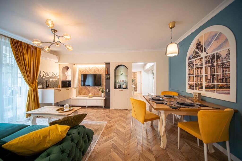 a dining room and living room with a table and yellow chairs at History Museum Apartment in Bucharest