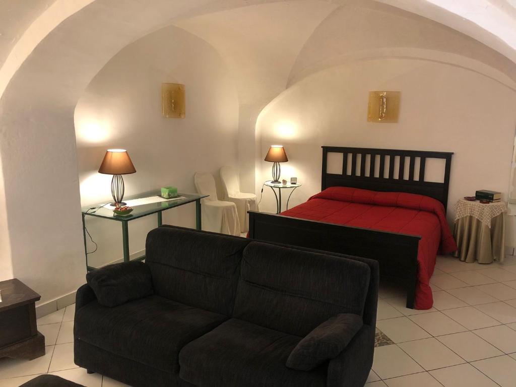 una camera con letto rosso e divano di Casa Vacanze Gaia a Biancavilla