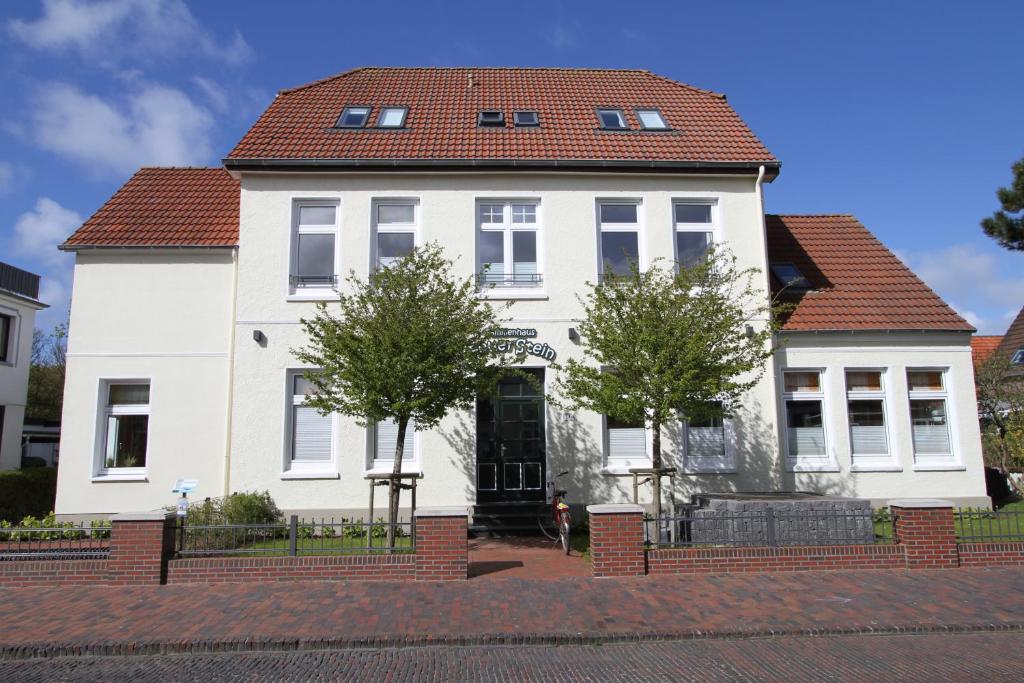 une maison blanche avec un toit rouge dans l'établissement Familienhaus Feuerstein, à Wangerooge