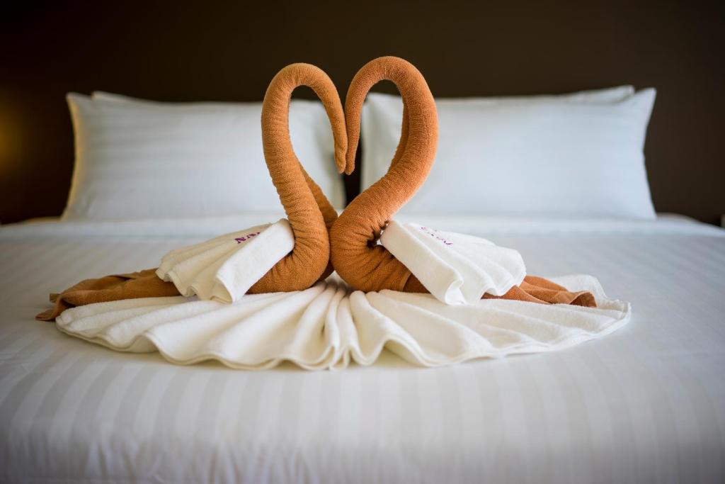 two swansuitsrendered to look like they are standing on a bed at Coral Inn in Karon Beach