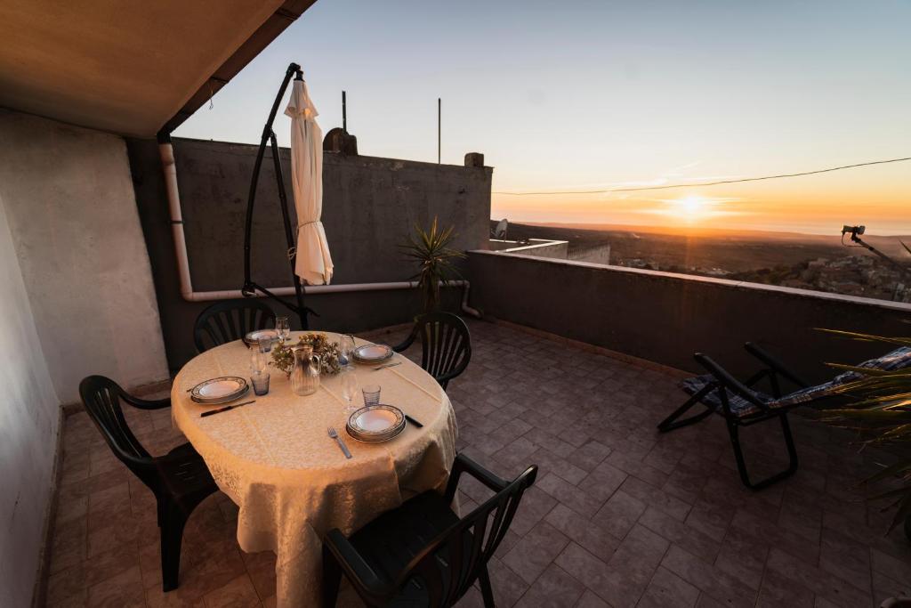 un tavolo e sedie su un balcone con vista sul tramonto di Su 'e Torigheddu - Casa con terrazza panoramica a Cuglieri