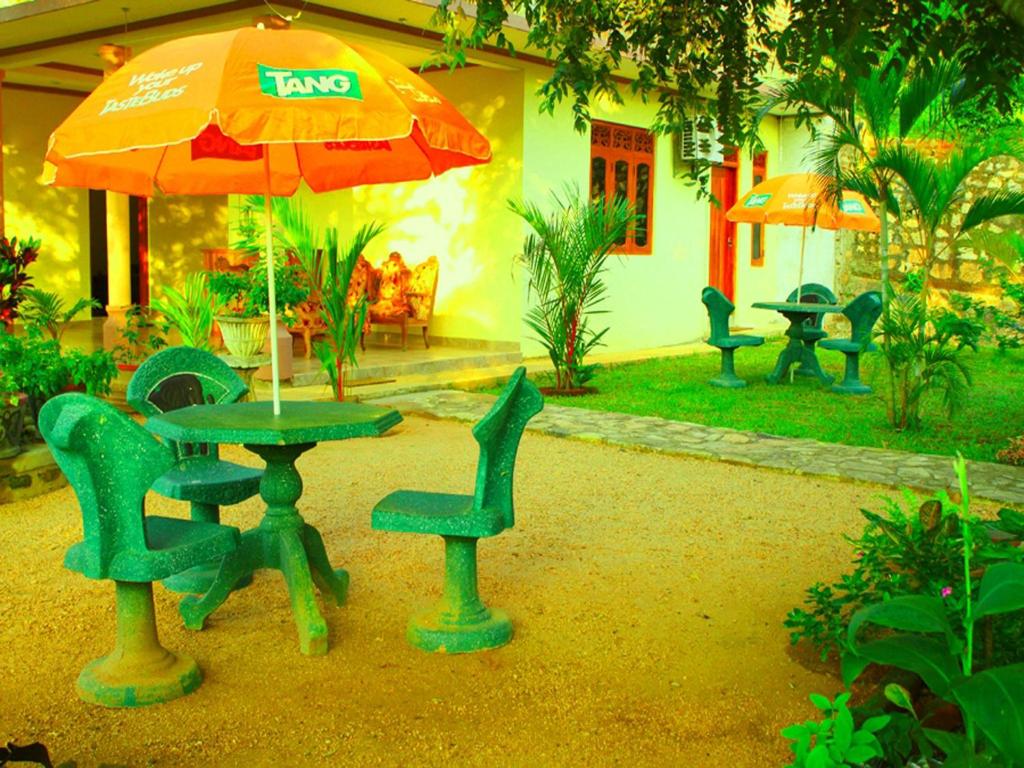 einen Tisch, Stühle und einen Regenschirm im Hof in der Unterkunft Mount View in Polonnaruwa