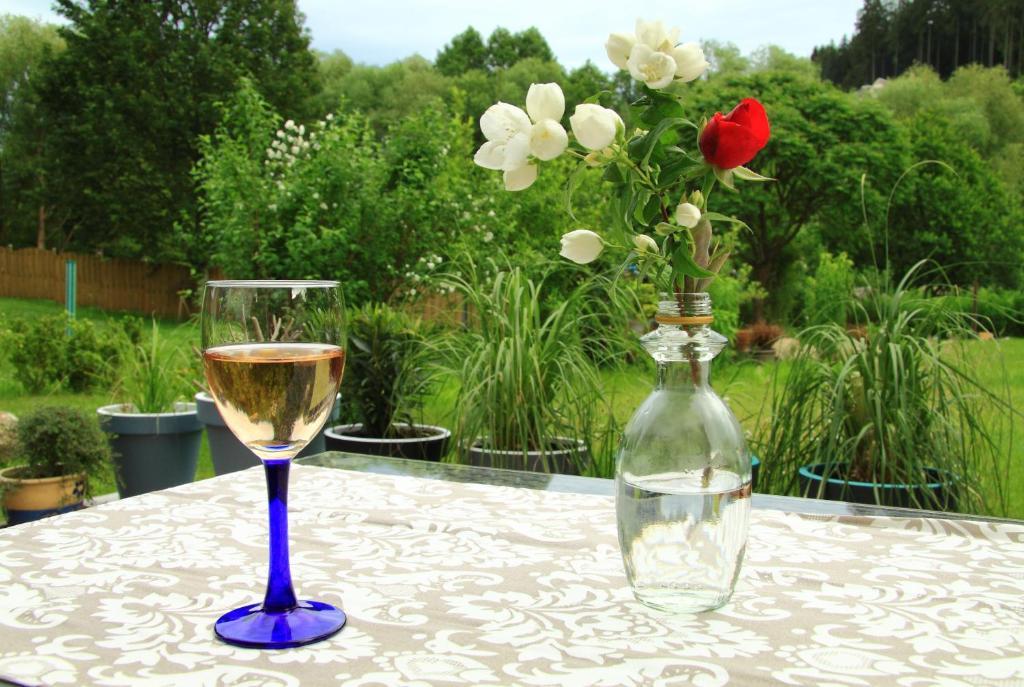 un bicchiere di vino e un vaso di fiori su un tavolo di Ferienwohnung Haus Felix a Bad Elster