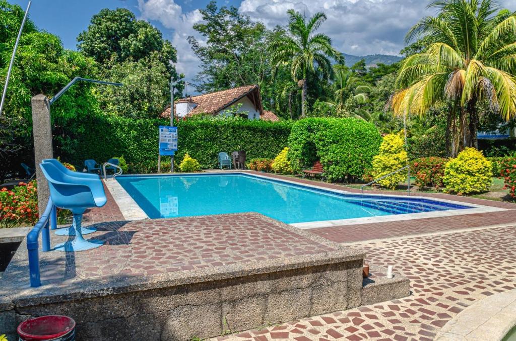 a swimming pool with a blue chair in front of a house at ALDEA VACACIONAL LA FLORIDA Apto 103 Bloque 1 in Santa Fe de Antioquia