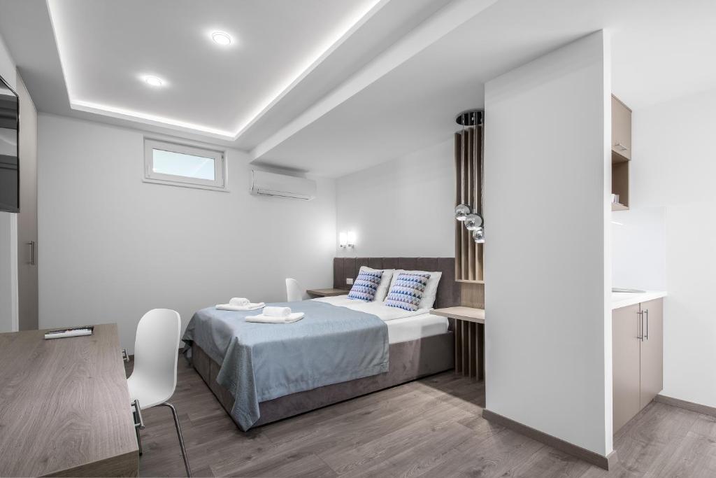 a white bedroom with a bed and a table and chairs at Hévízi Tópark Panzió II. in Hévíz