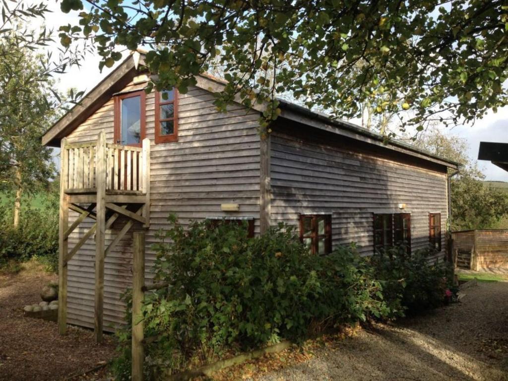 een klein houten huis met een veranda en een raam bij 3-Bed Lodge with direct access to the Tarka trail in Great Torrington