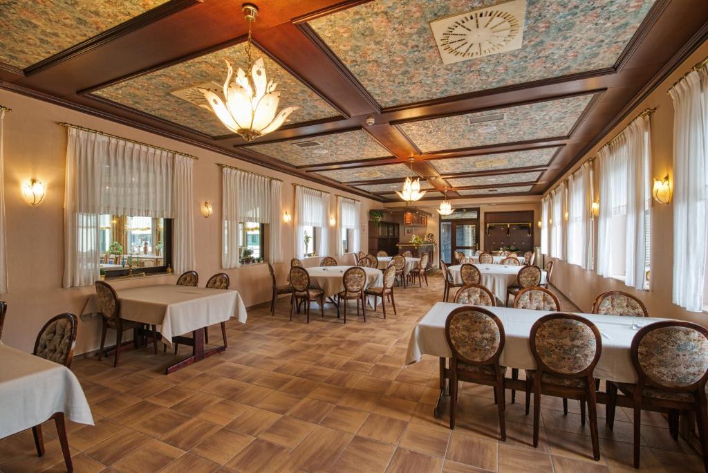 a dining room with tables and chairs and a ceiling with a clock at Hotel Haus Tiefenbach in Bullange