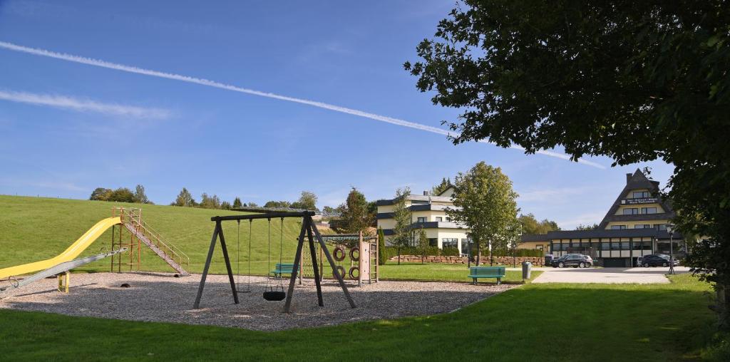 a playground with a swing set in a park at Hotel Haus Tiefenbach in Bullange