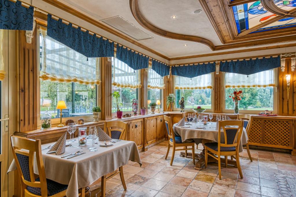 a restaurant with tables and chairs and windows at Hotel Haus Tiefenbach in Bullange