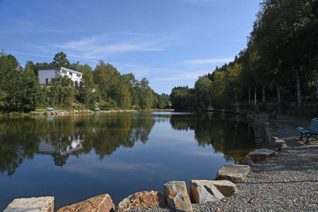 a view of a river with a bench next to it at Hotel Haus Tiefenbach in Bullange