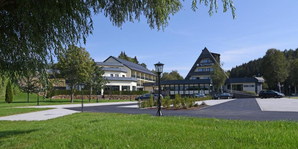 a building on a street with cars parked in a park at Hotel Haus Tiefenbach in Bullange