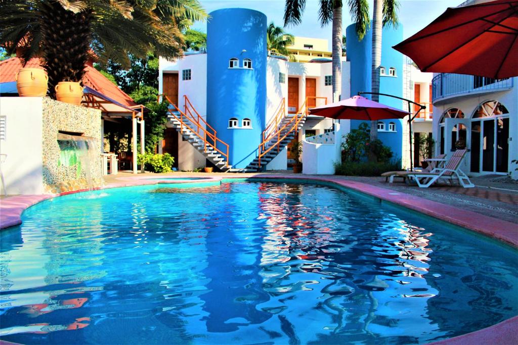 - une piscine en face d'un bâtiment avec un parasol dans l'établissement Hotel Mexico Lindo, à Santa Cruz Huatulco