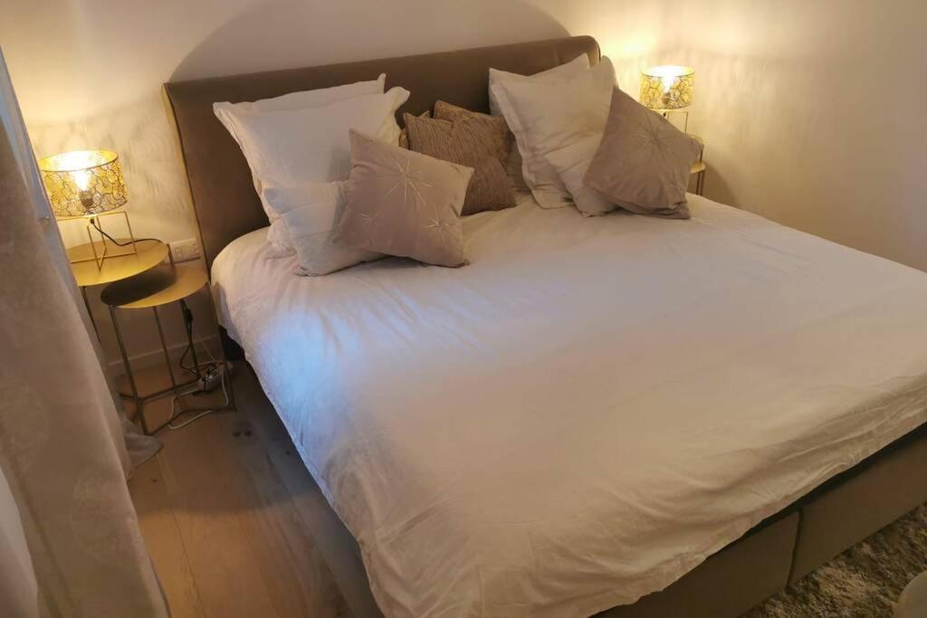 Elle comprend un grand lit avec des draps et des oreillers blancs. dans l'établissement Magnifique F3, 75m² avec Parking privé et Terrasse, à Strasbourg