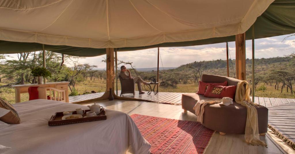 una camera con un letto e una donna in una tenda di Kicheche Valley Camp a Naboisho