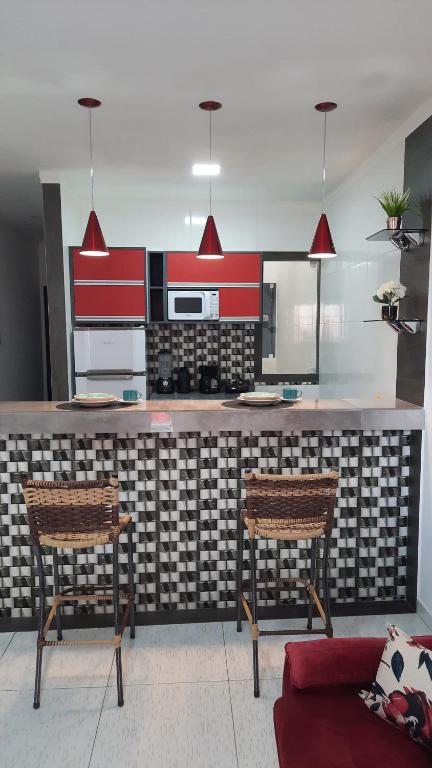 a kitchen with a counter with two chairs and a couch at Lindo Apartamento Varanda no centro de Paulo Afonso in Paulo Afonso