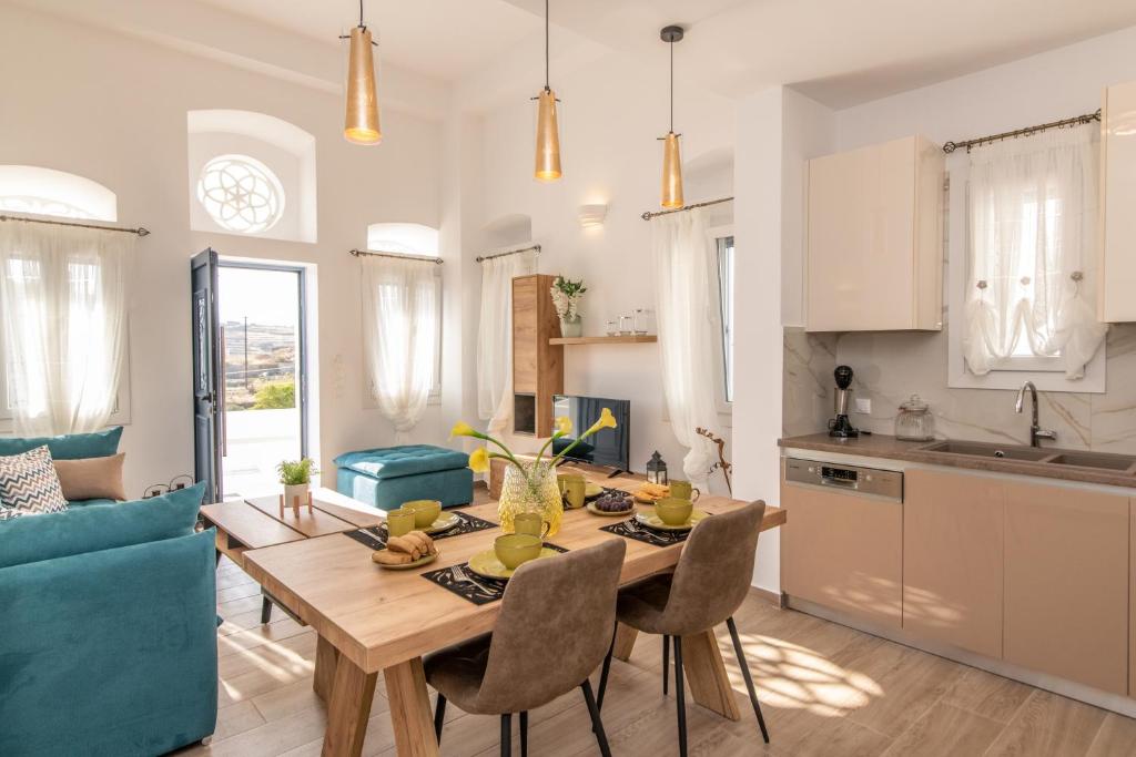 cocina y sala de estar con mesa de madera y sillas en Villa Anemona Tinos en Kalloni Tinou