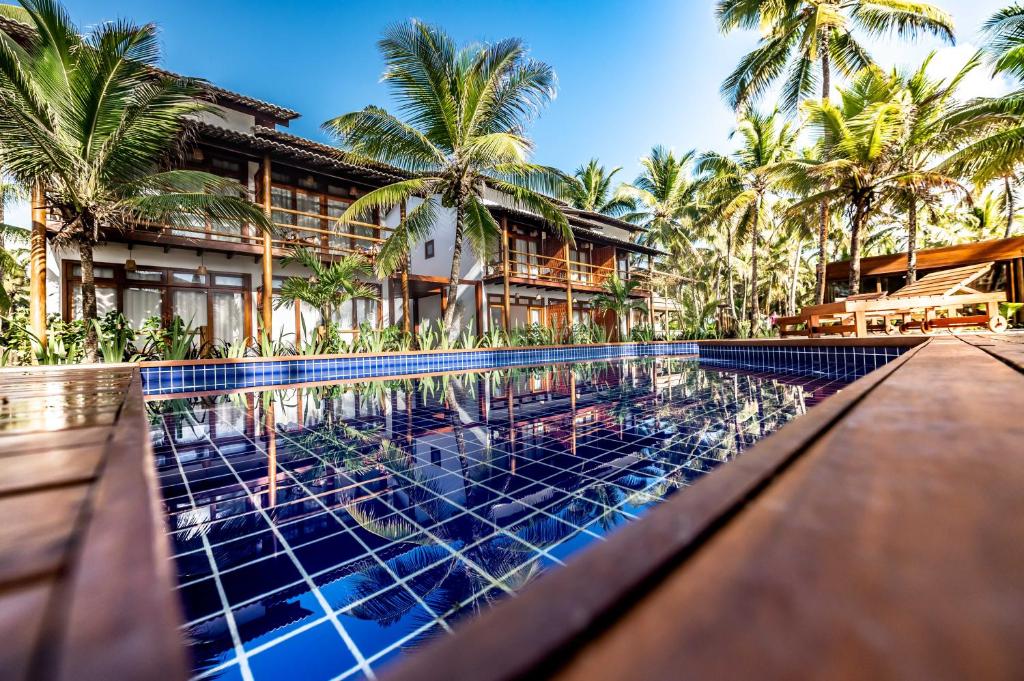 a swimming pool in front of a resort with palm trees at Dreamland Bungalows - Taipú de Fora - Barra Grande in Barra Grande