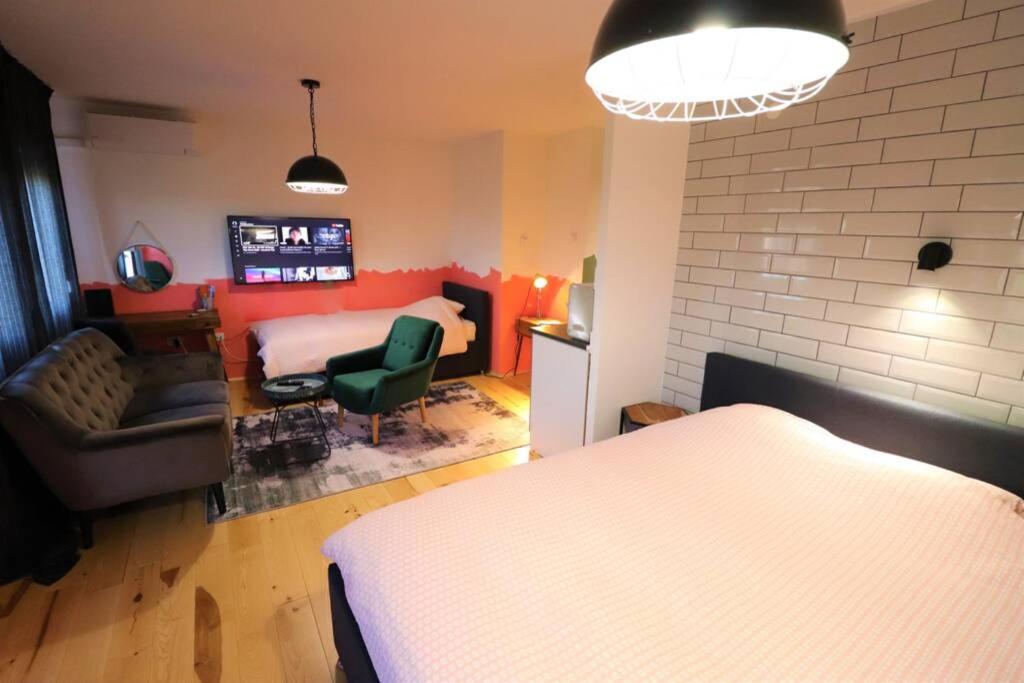 a bedroom with a bed and a living room with a couch at Room Emma,between bus and train station,Netflix,speed Wi-Fi in Zagreb