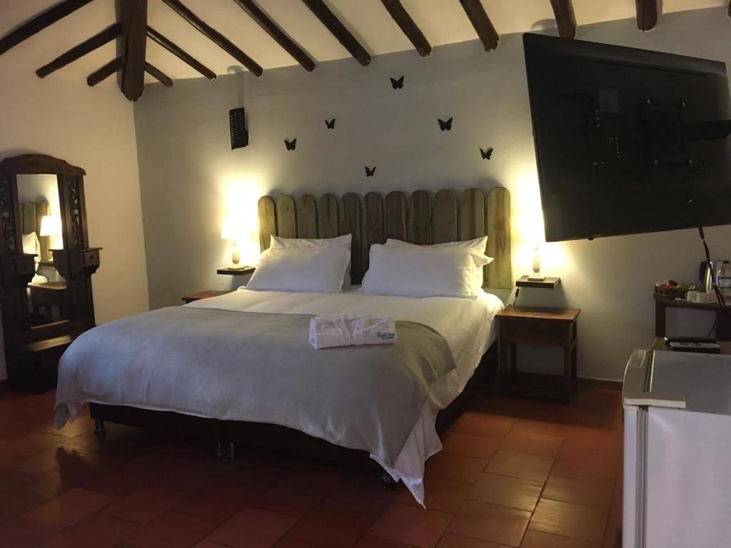 um quarto com uma cama grande e uma televisão de ecrã plano em HOTEL AQUA VITAE em Villa de Leyva