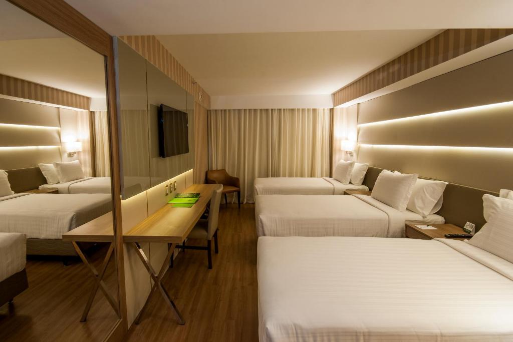 um quarto de hotel com três camas e uma secretária em Américas Copacabana Hotel no Rio de Janeiro