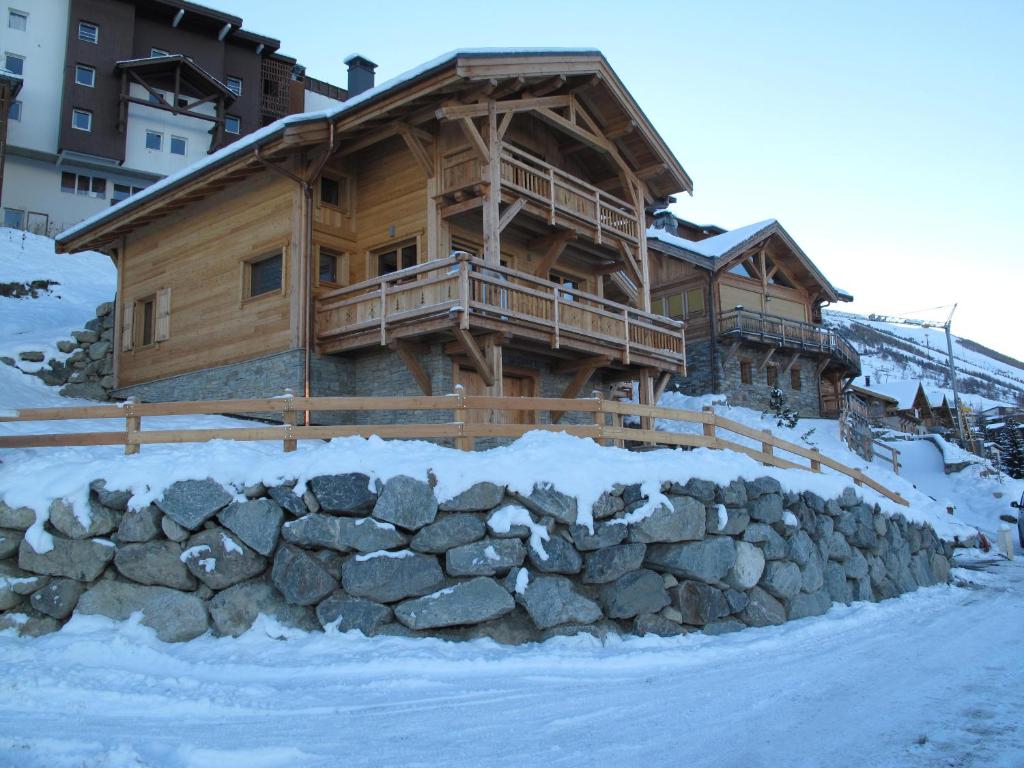 una cabaña de madera en la nieve con una pared de piedra en CHALET L'ALPAGA 1 en Les Deux Alpes