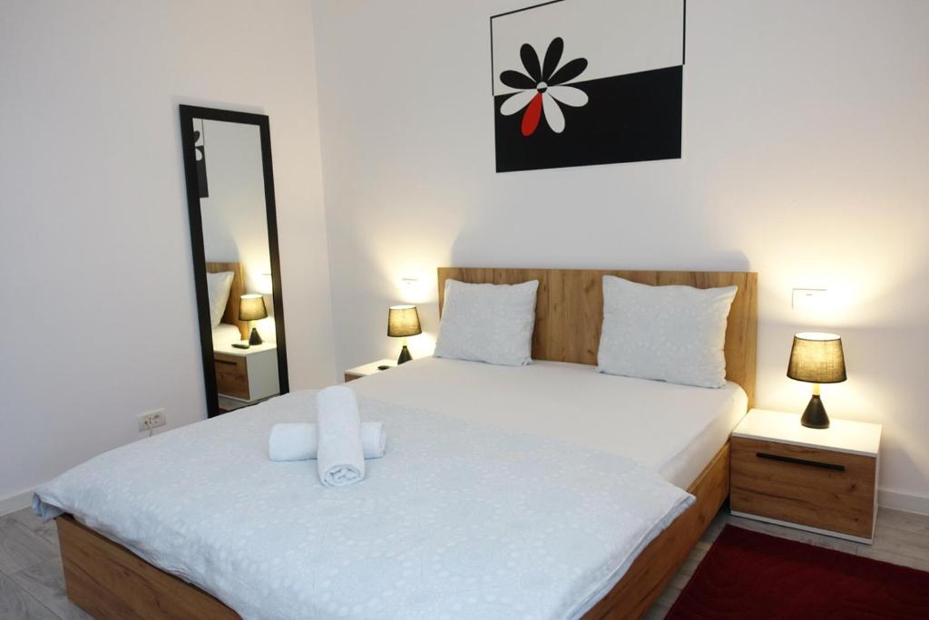 - une chambre avec un lit doté de draps blancs et d'un miroir dans l'établissement Balcescu Apartment Self Check-in, à Timişoara