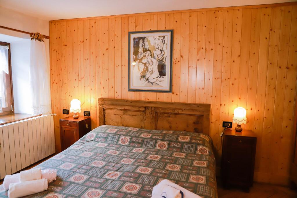 ファルカーデにあるCOL DE RIF Piccolo Appartamento Storico Dolomitiの木製の壁のベッドルーム1室(ベッド1台付)