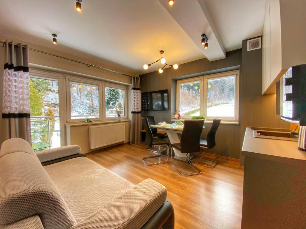 salon ze stołem, krzesłami i oknami w obiekcie Kurort Kozubnik Apartament 33 Wellness &SPA w mieście Porąbka