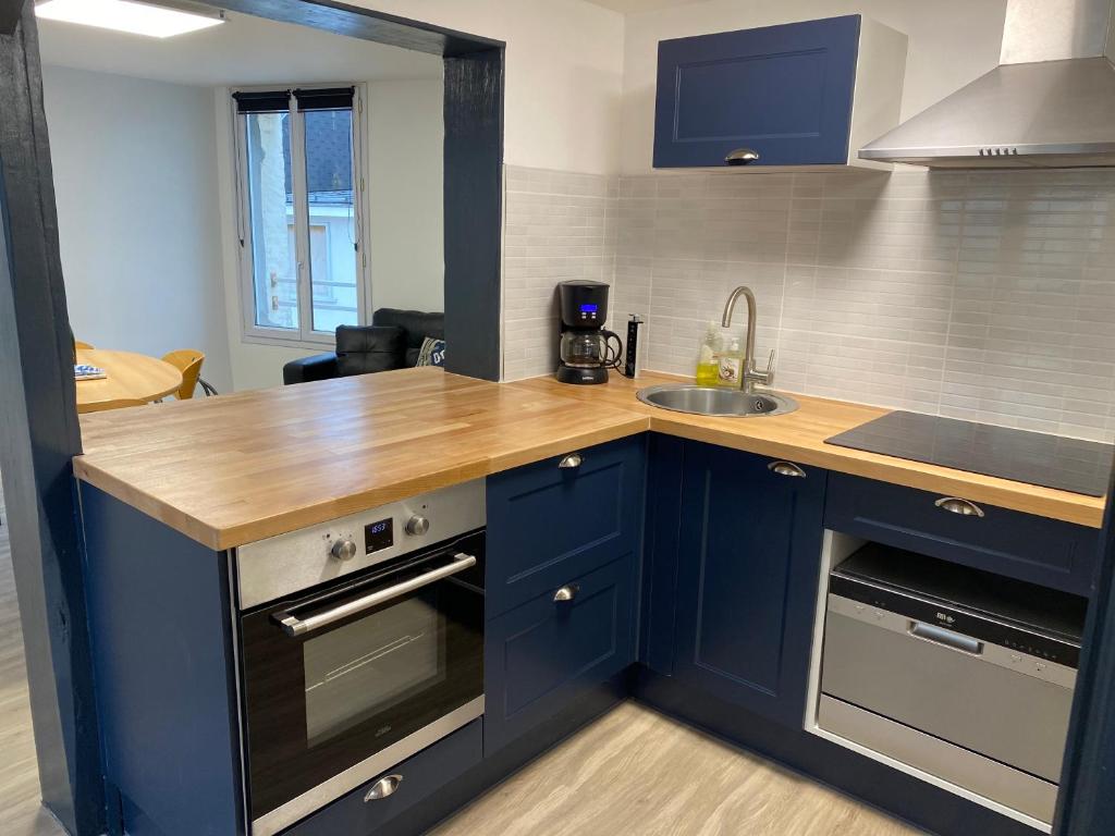 une cuisine avec des placards bleus et un comptoir en bois dans l'établissement L’Escapade Normande, au Tréport