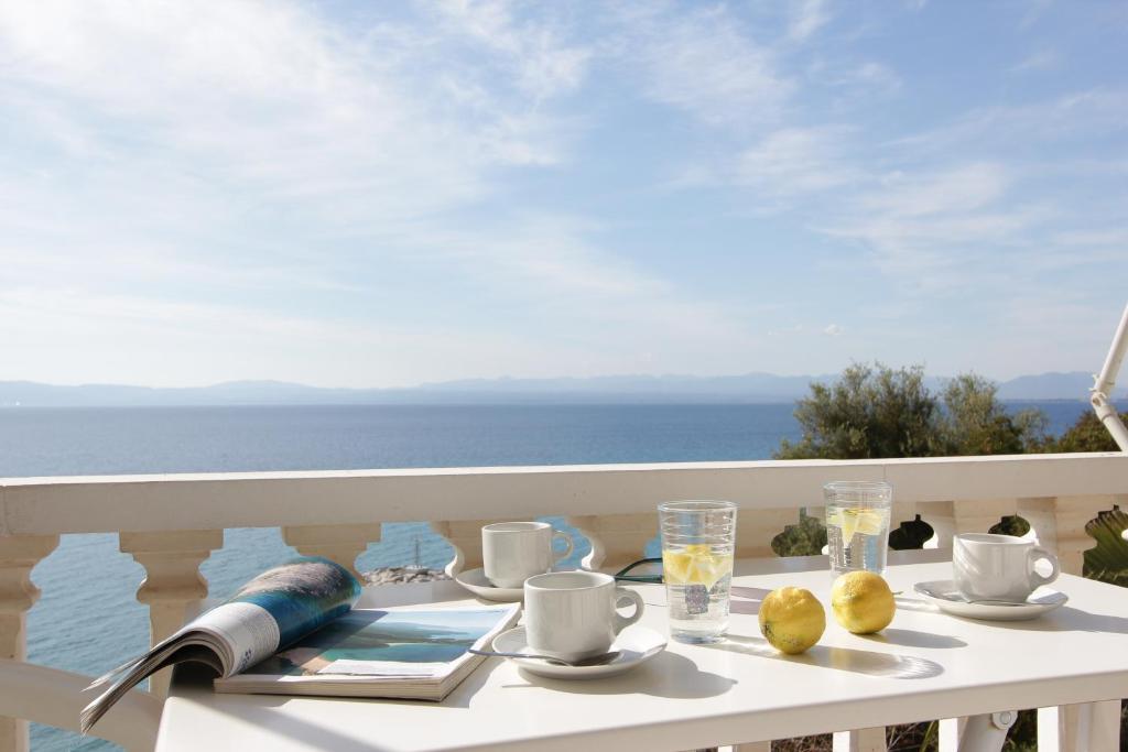 a table on a balcony with a view of the ocean at Apollon Apartments in Akrogiali