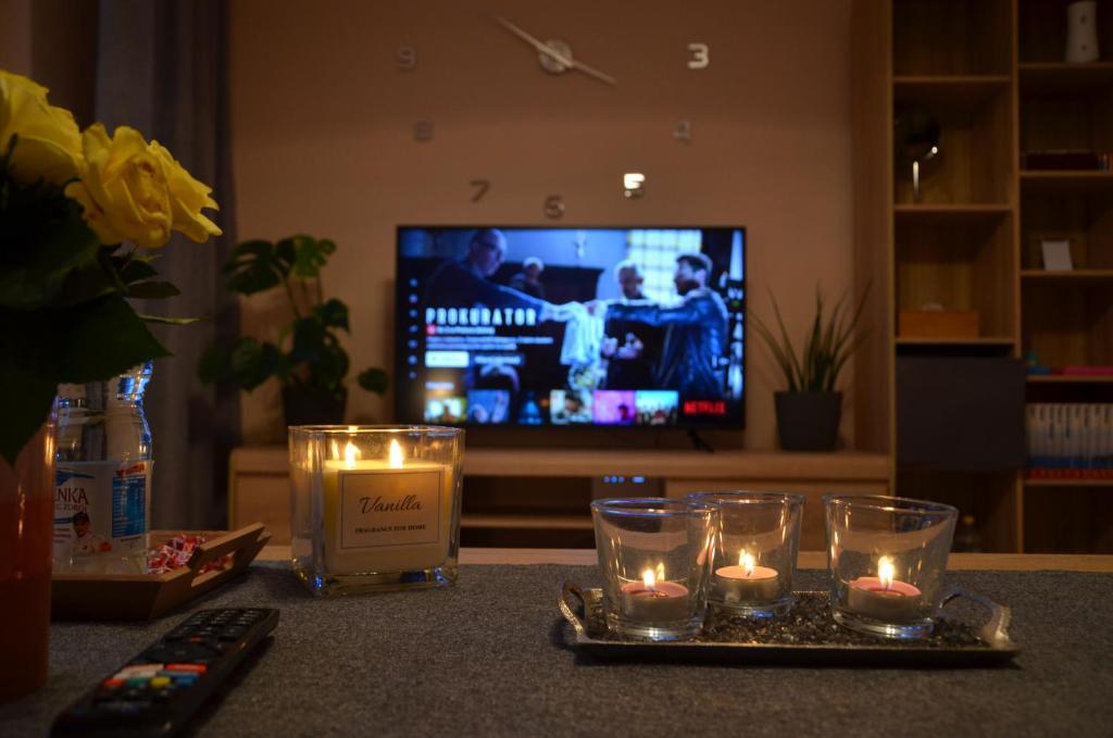 a table with candles and a tv in a living room at Apartament Modlin in Nowy Dwór Mazowiecki