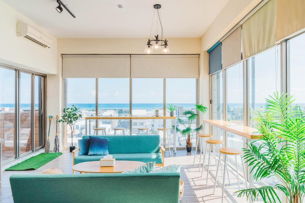 uma sala de estar com um sofá azul, mesas e janelas em Fun Trip - Fu May Sea View Holiday house l 無敵海景交誼廳 l 附汽機車租賃 l em Taitung City