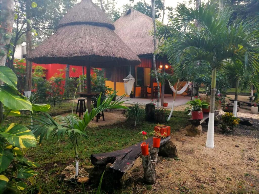 un jardin avec une cabane dotée d'un banc et d'arbres dans l'établissement Hotel "Casa Las Lolas", à Xpujil