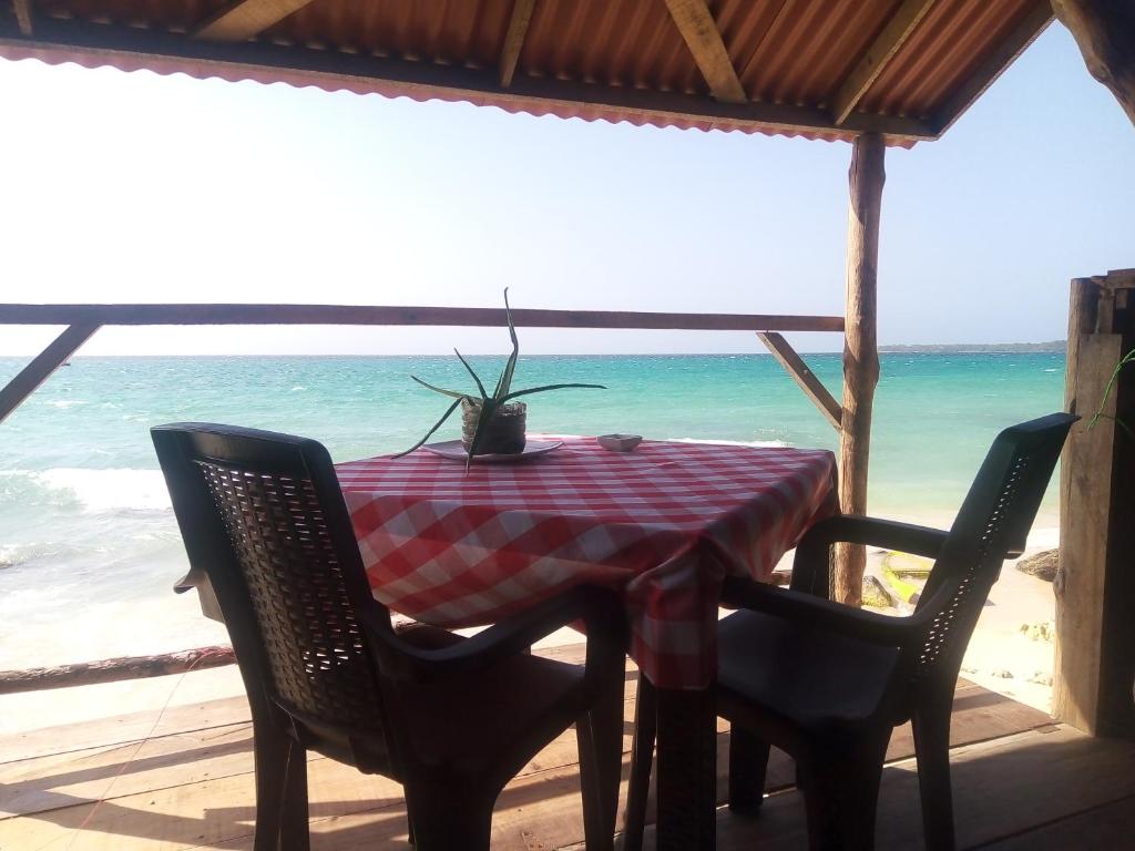 a table with a chair and umbrella on a beach at Nuestra Cabañita in Playa Blanca