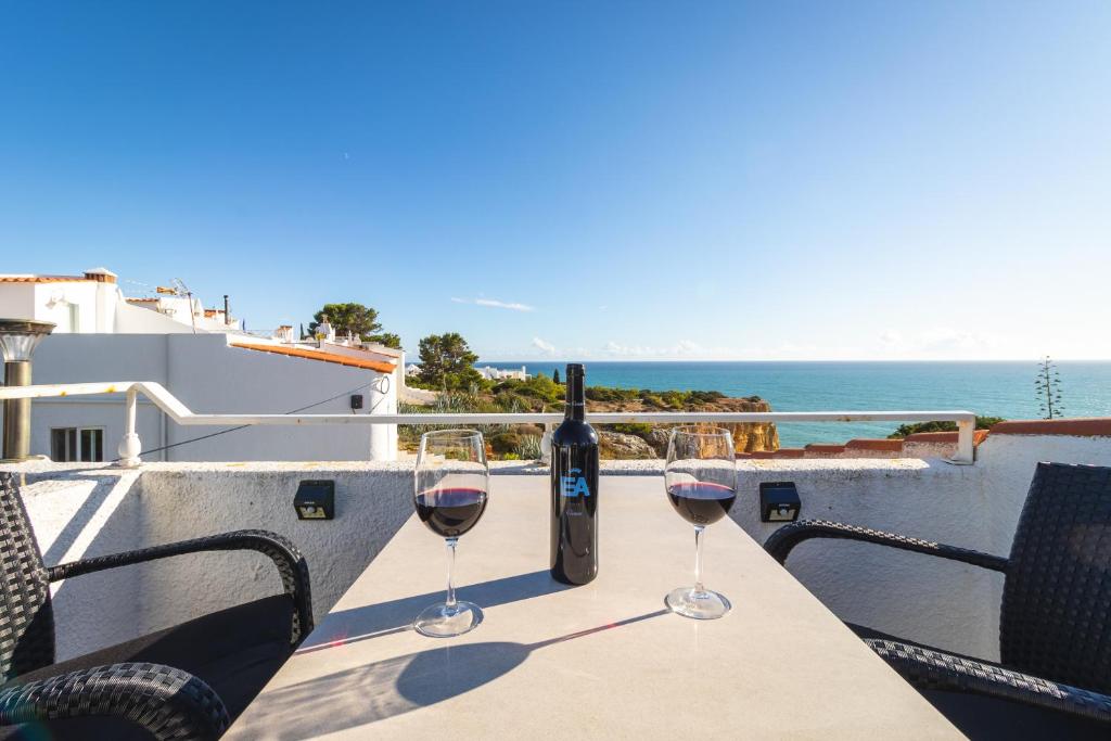 dois copos de vinho numa mesa com vista para o mar em Apartment Casa Beatriz direkt auf der Klippe em Carvoeiro