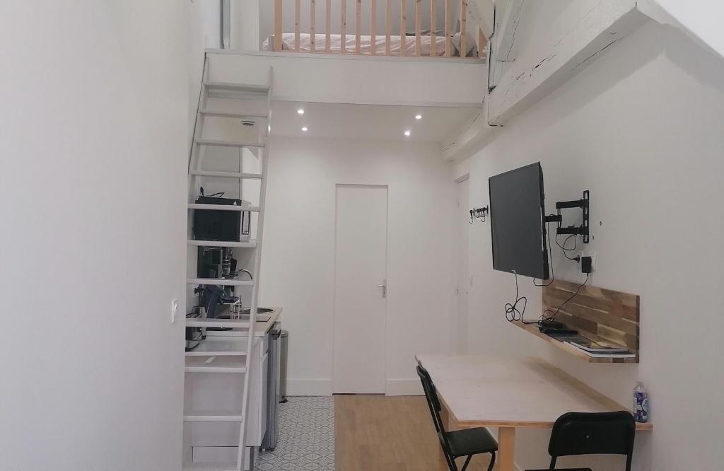 Dieses weiße Zimmer verfügt über einen Schreibtisch und einen Tisch mit Stühlen. in der Unterkunft Studio plein de charme - 2 in Orléans