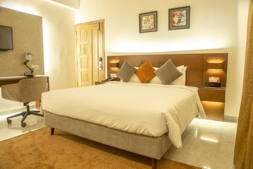 a bedroom with a large white bed and a desk at Jatra Flagship Chattogram City Centre in Chittagong