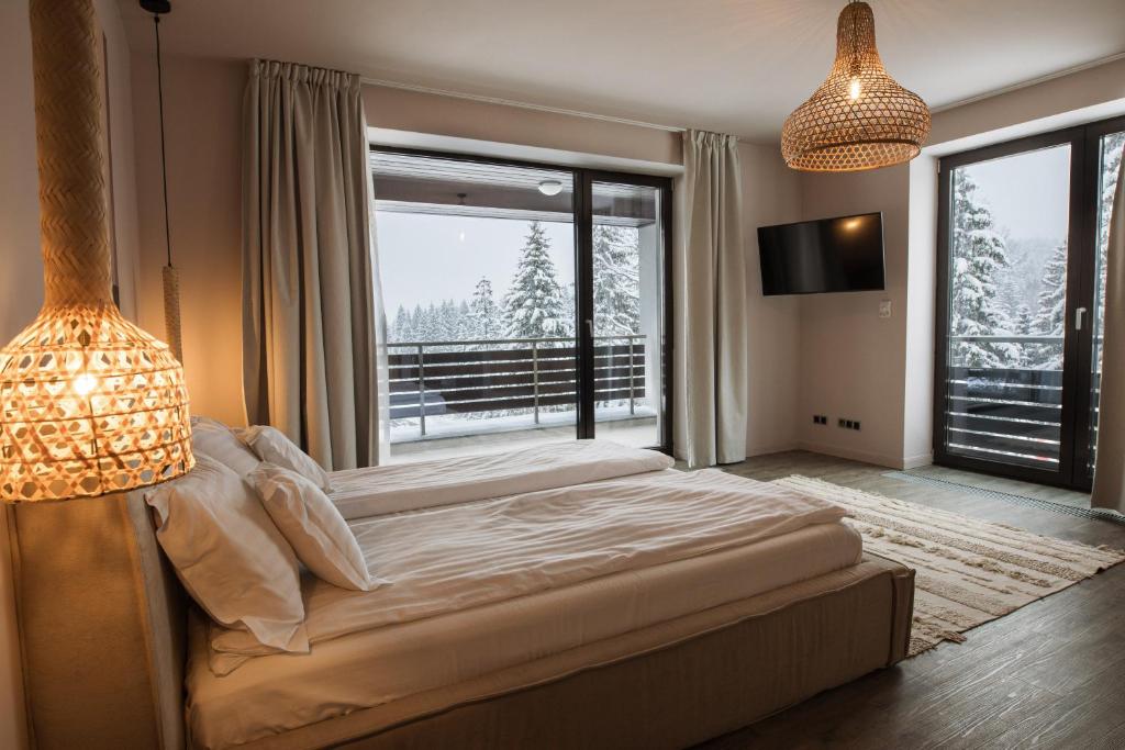 een slaapkamer met een groot bed en een groot raam bij Silver Pine Apartment in Poiana Brasov