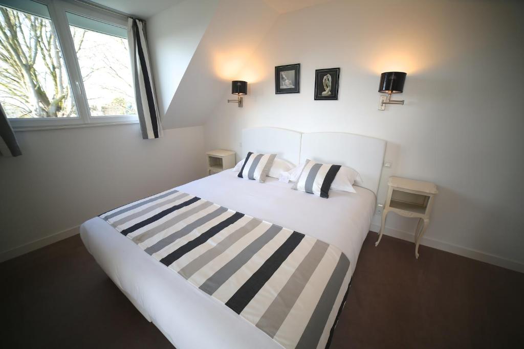 a bedroom with a white bed with striped sheets and a window at Hotel Restaurant Le Lion d'Or in Saint-Hilaire-du-Harcouët