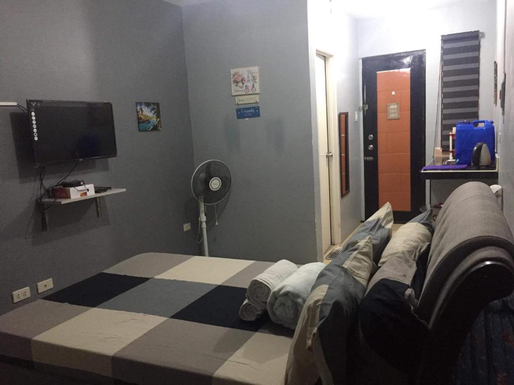 Habitación con cama y TV. en Lucena Meg's Studio Apmnt Deluxe rm-Near SM-Wifi, en Lucena