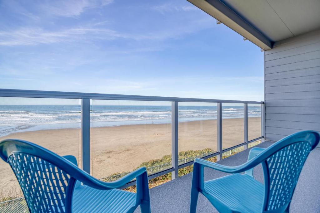 2 sillas azules en un balcón con vistas a la playa en Nye Suite, en Newport